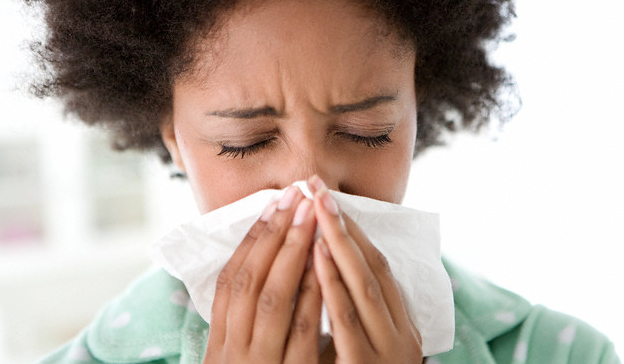 A woman in pajamas blowing her nose