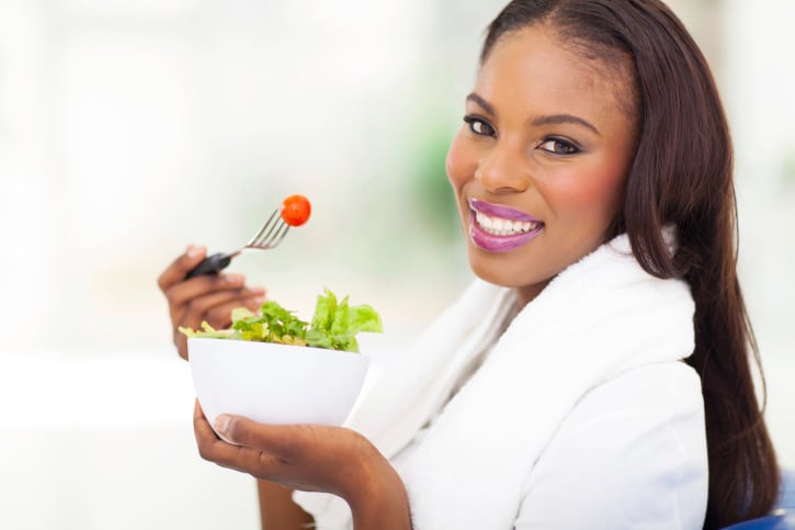 African American woman with long hair eating salad