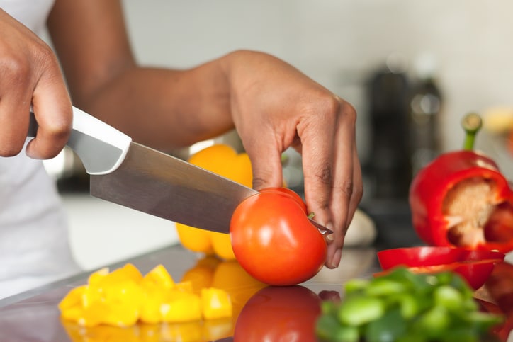 Prep cook slicing tomato and peppers