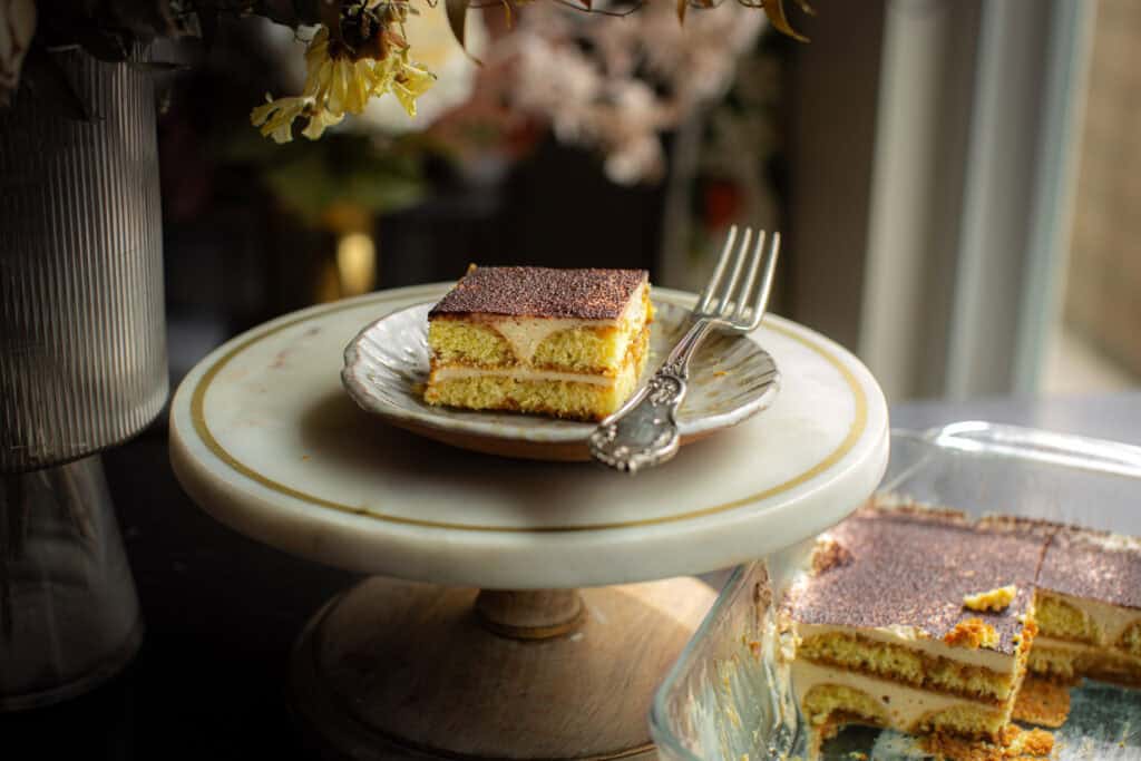 Dreamy Homemade Vegan Tiramisu Recipe (Easy & Delicious) 2 plated tiramisu with a fork sitting on a cake stand