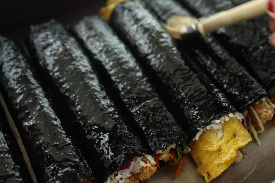 How to Make 4 Stunning Korean Kimbap Recipes. 4 row of kimbap rolls being brushed with sesame oil
