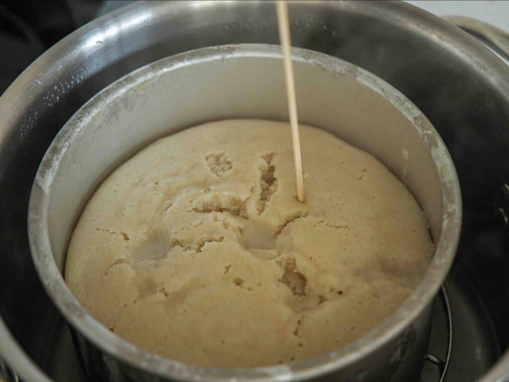 The Perfect NO BAKE Easy Vegan Sponge Cake Recipe. 4 inserting wooden skewer into steamed vegan sponge cake