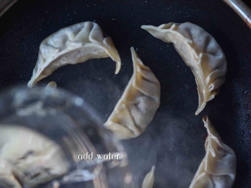 Homemade Vegan Dumplings Recipe - Kimchi Mandu. 36 adding-water-to-pan-of-potstickers