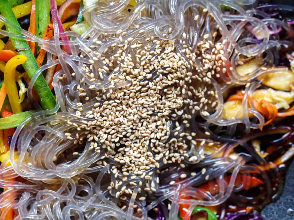 Healthy And Easy Vegan Japchae (Korean Glass Noodles). 7 cooked noodles in pan with vegetables and sauce for vegan japchae