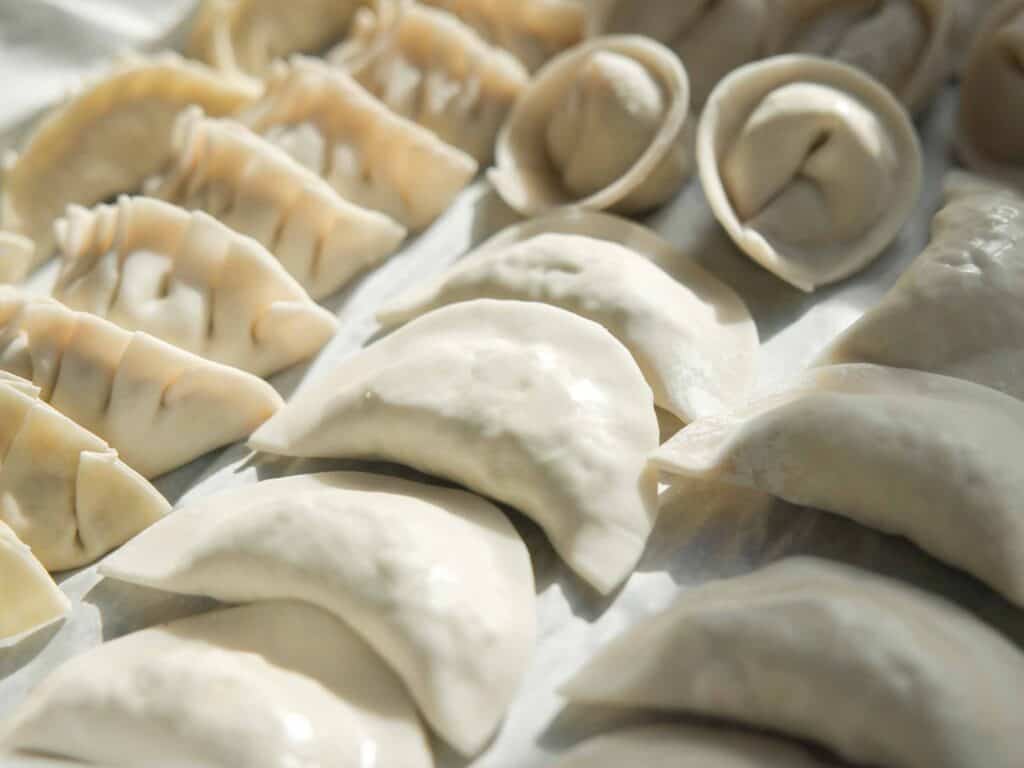 Homemade Vegan Dumplings Recipe - Kimchi Mandu. 30 folded-dumplings-on-a-parchment-lined-tra