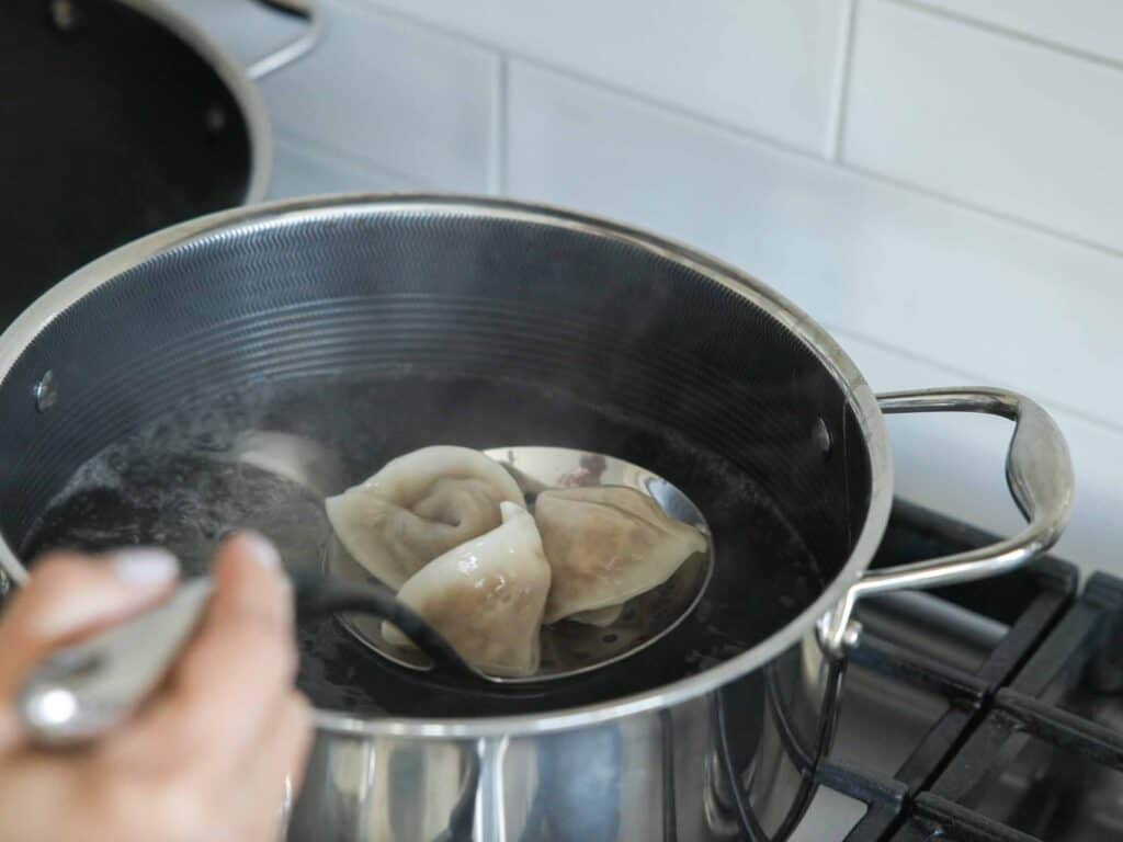 Homemade Vegan Dumplings Recipe - Kimchi Mandu. 40 removing-boiled-dumplings-from-pot-of-water