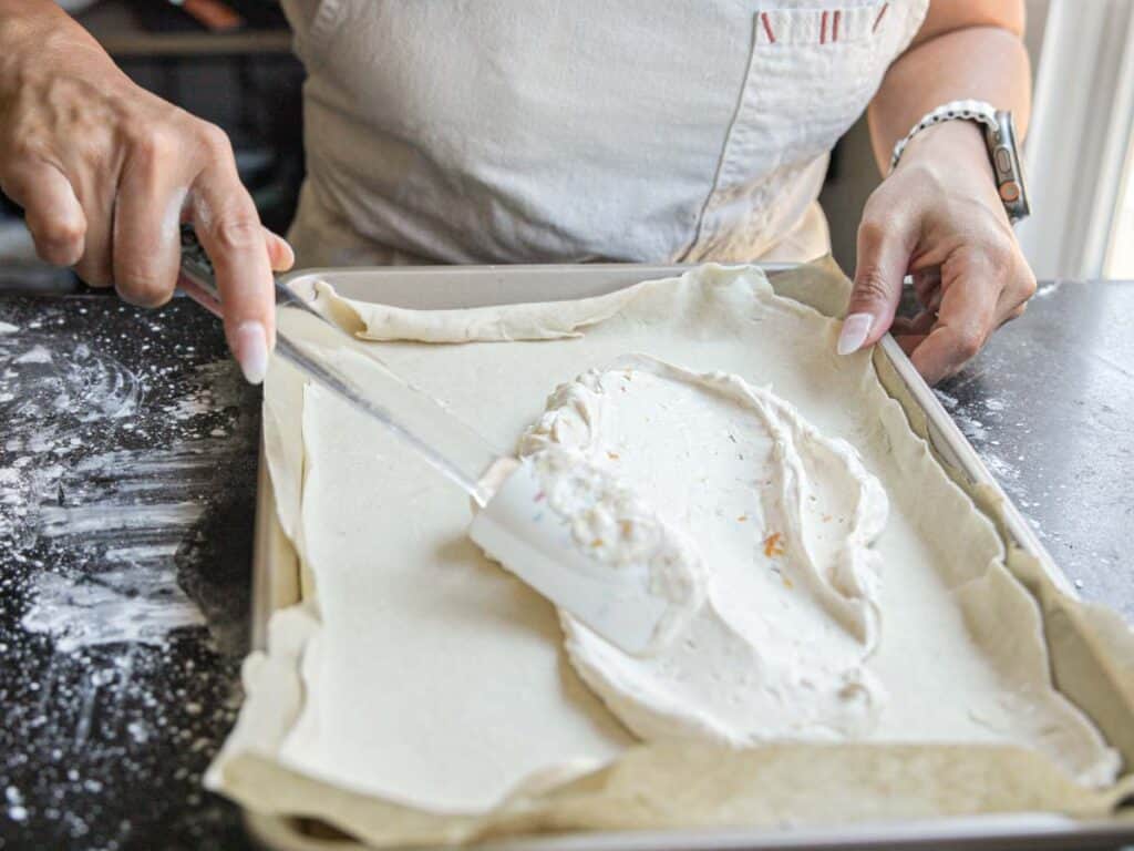 6-Ingredient Easy Cream Cheese Peach Galette Recipe. 14 spreading-cream-cheese-filling-onto-peach-galette-pastry