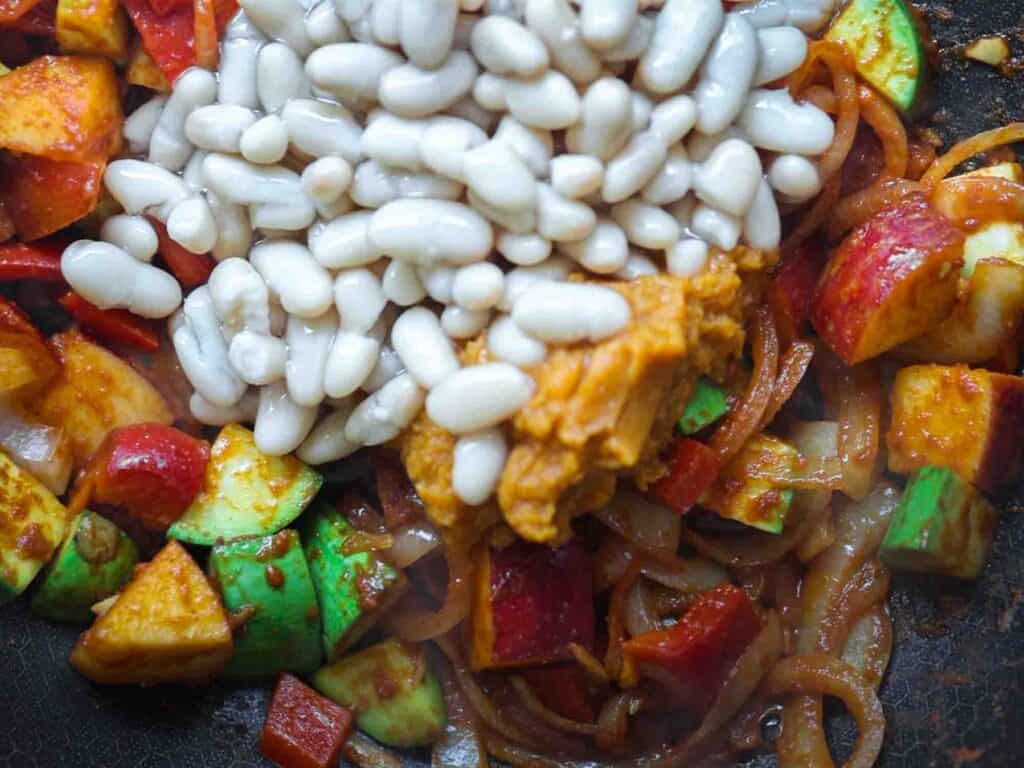 Hi-Protein Delicious Vegan Pumpkin Curry with Tofu. 21 adding cannellini beans to pan of veggies for curry