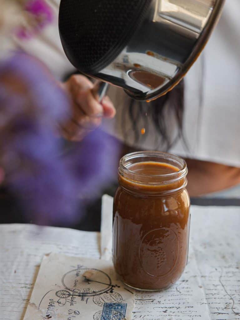 Easy Vegan Pumpkin Spice Syrup (Starbucks Copycat!). 3 pouring last drops of vegan pumpkin spice syrup into mason jar