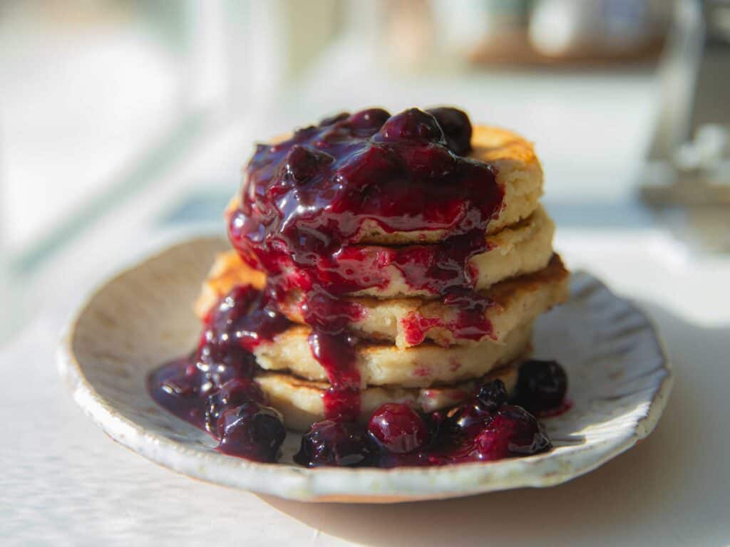 30-Minute Fluffy and Delicious Vegan Lemon Ricotta Pancakes. 2 side view of vegan lemon ricotta pancakes with blueberry sauce