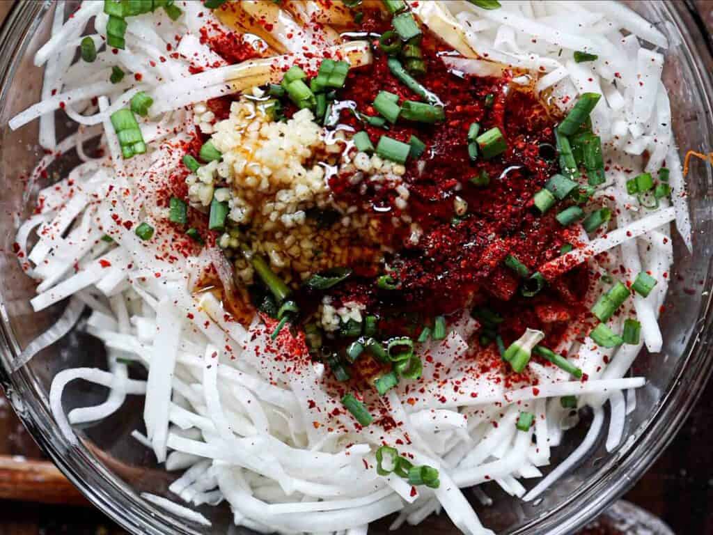 Easy & Spicy Korean Radish Salad - Musaengchae Recipe. 6 all ingredients in bowl for korean radish salad