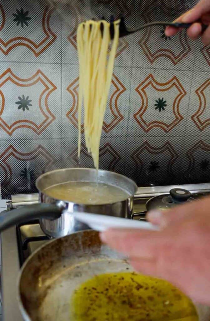 Spaghetti Aglio e Olio: The PERFECT 6-Ingredient Pasta Recipe. 14 adding pasta to pan of infused oil