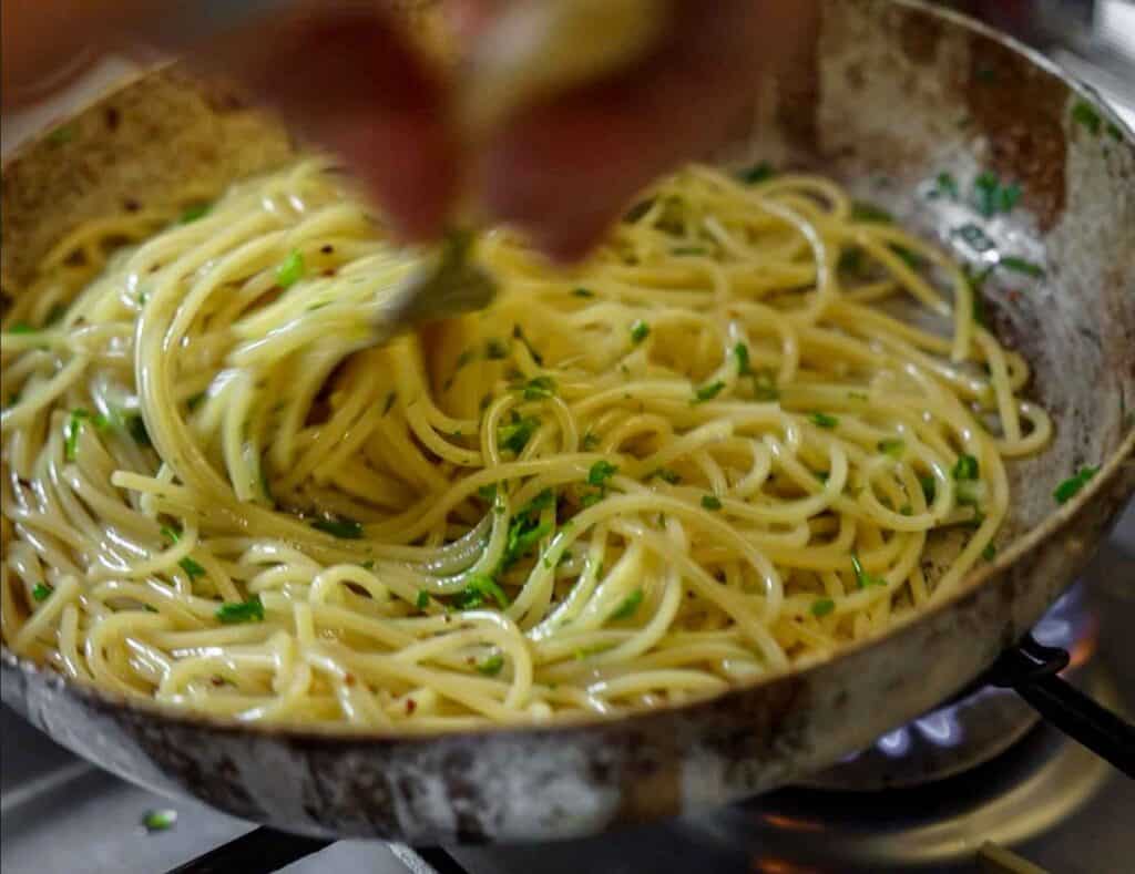 Spaghetti Aglio e Olio: The PERFECT 6-Ingredient Pasta Recipe. 17 stirring aglio e olio for emulsification