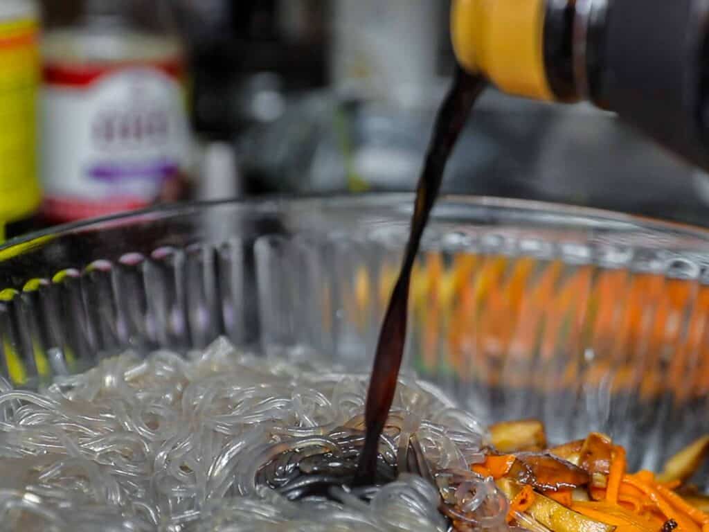 My Mom's Easy Vegetarian Japchae (Glass Noodles). 22 adding soy sauce to japchae