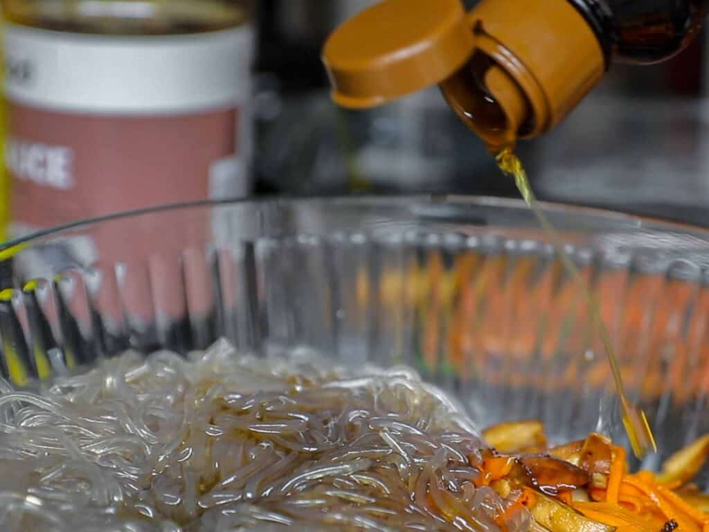 My Mom's Easy Vegetarian Japchae (Glass Noodles). 24 adding sesame oil to japchae