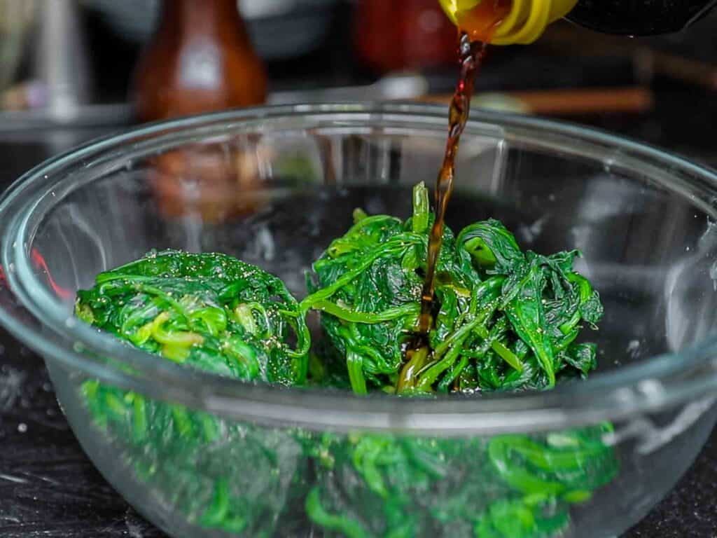 My Mom's Easy Vegetarian Japchae (Glass Noodles). 7 adding soy sauce to boiled spinach