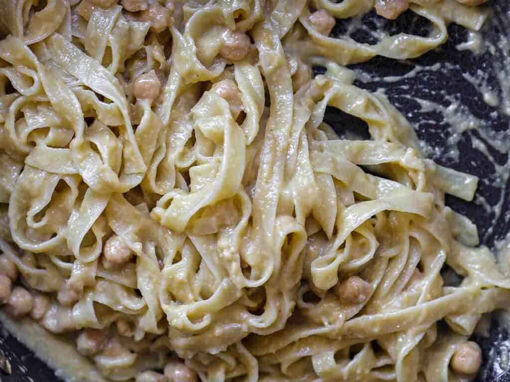 5-Ingredient Easy Chickpea Pasta Recipe (Pasta e Ceci). 16 Close-up of creamy pasta mixed with chickpeas, showcasing a rich, sauce-coated texture. The dish has a rustic, homemade appearance with the noodles intertwined and the chickpeas partially visible amidst the sauce.