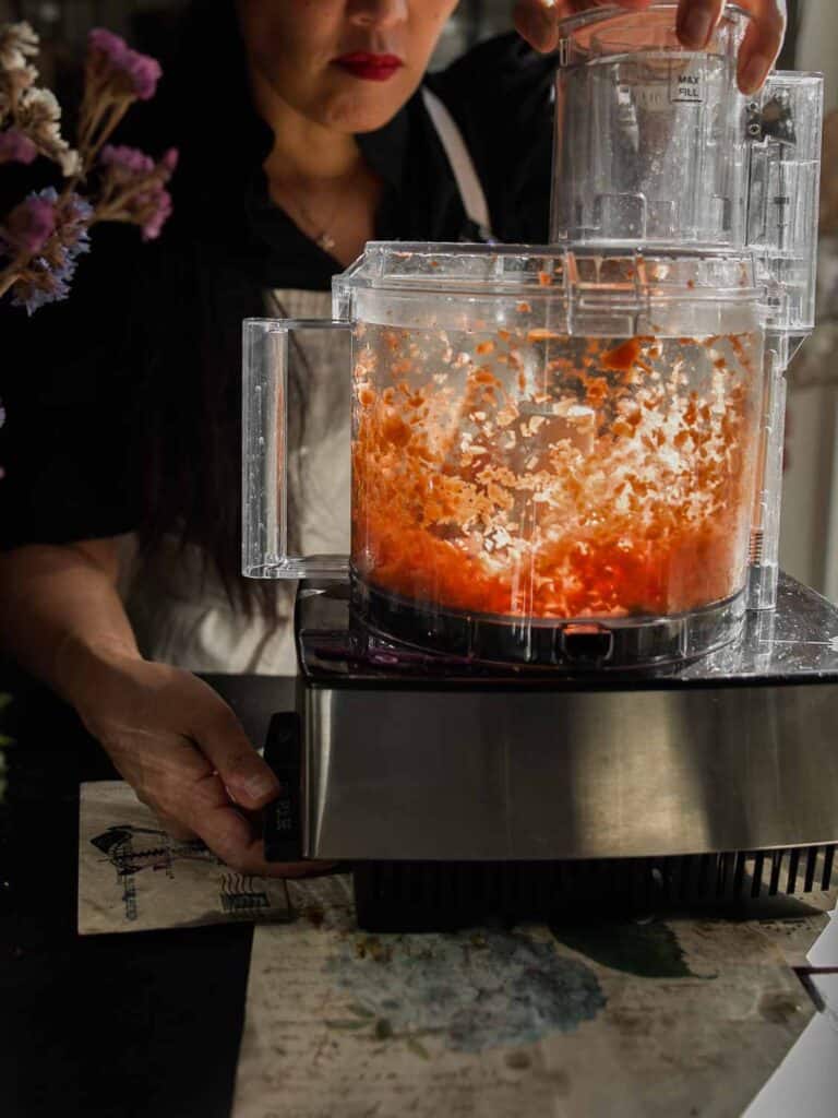 The BEST Vegan Carrot Cake Recipe - Not Too Sweet! 4 A person uses a food processor to shred carrots,