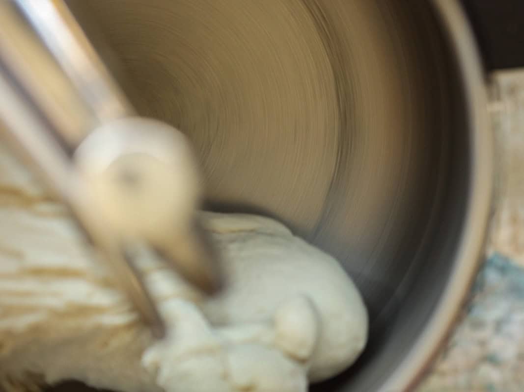 Perfect Roasted Garlic Vegan Dinner Rolls Recipe. 18 A close-up of a standmixer in motion, with a partially formed dough