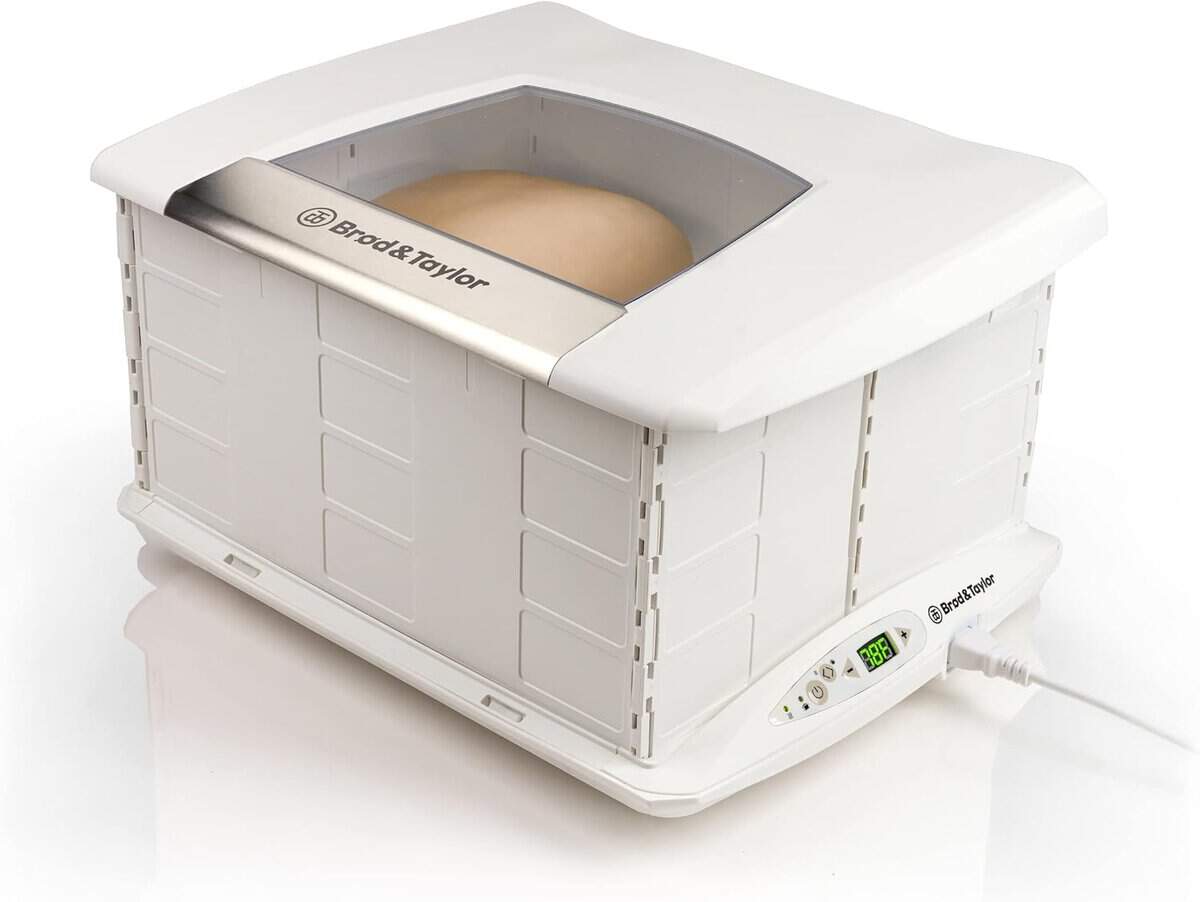 The Korean Vegan's 2025 VEGAN Holiday Gift GUIDE. 12 A white bread proofer with dough inside makes a perfect holiday gift, featuring a transparent top window and digital temperature controls on the side, plugged into a power source. The exterior design has vent-like patterns that add an elegant touch to any kitchen countertop.
