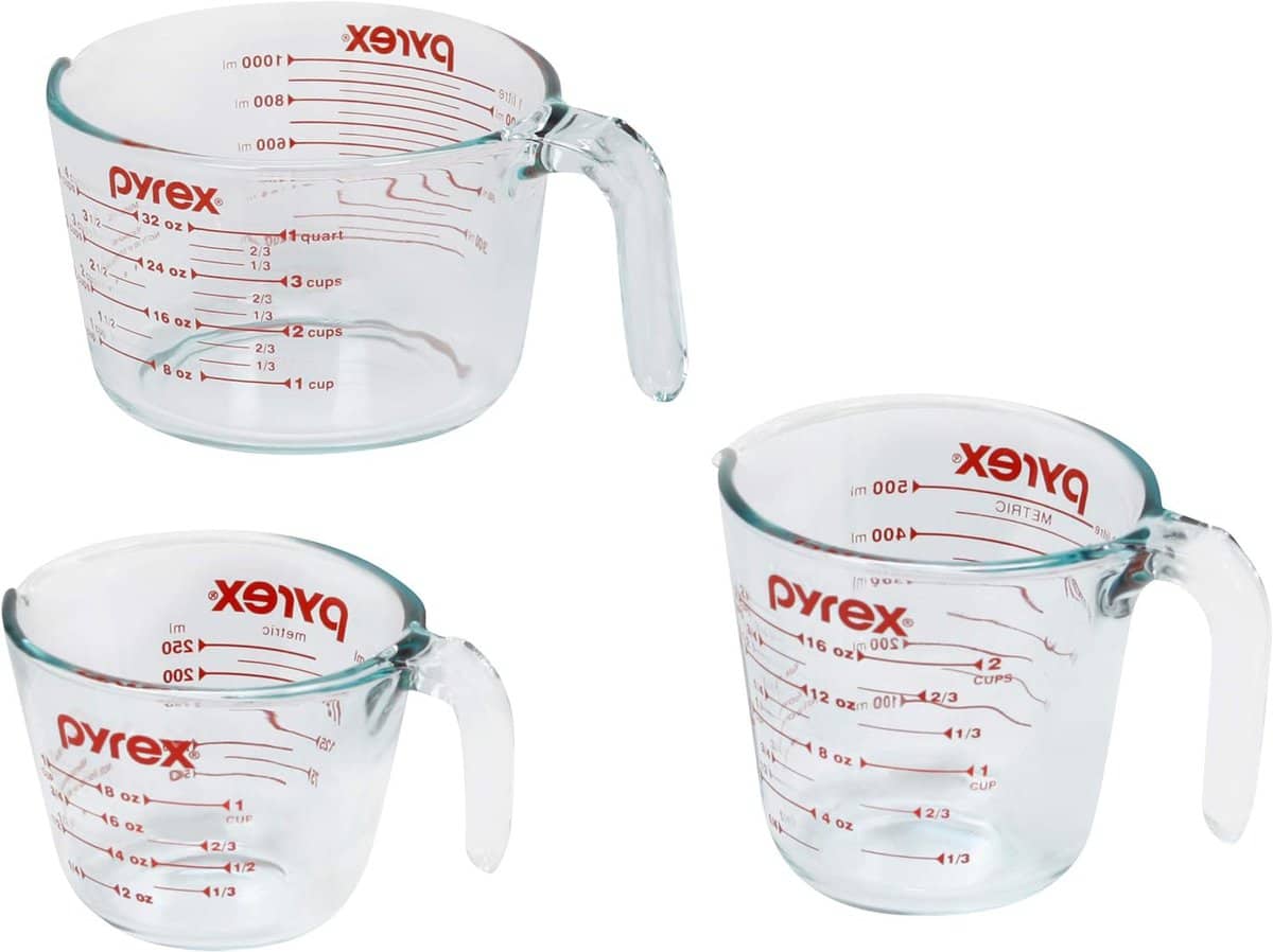 The Korean Vegan's 2025 VEGAN Holiday Gift GUIDE. 9 Three clear Pyrex glass measuring cups with red markings, showing various measurements in cups, ounces, and milliliters. Featured in the 2024 Holiday Gift Guide, these essentials rest elegantly on a white background.