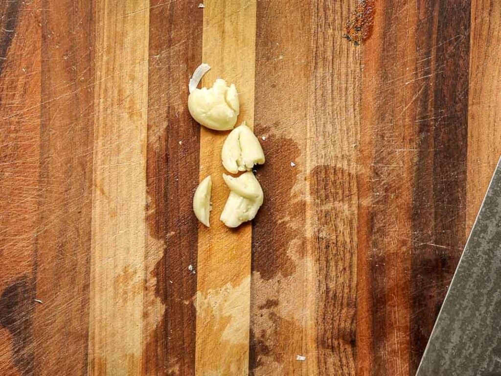30-Minute Creamy Gochujang Vodka Pasta - Delicious & Dairy-FREE. 9 Chopped garlic cloves on a wooden cutting board with a knife visible on the side.