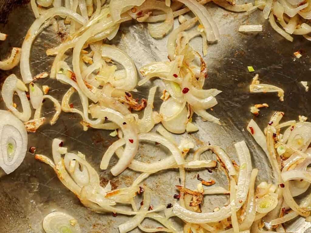 30-Minute Creamy Gochujang Vodka Pasta - Delicious & Dairy-FREE. 14 Close-up of julienned shallots and garlic being sautéed in a pan.