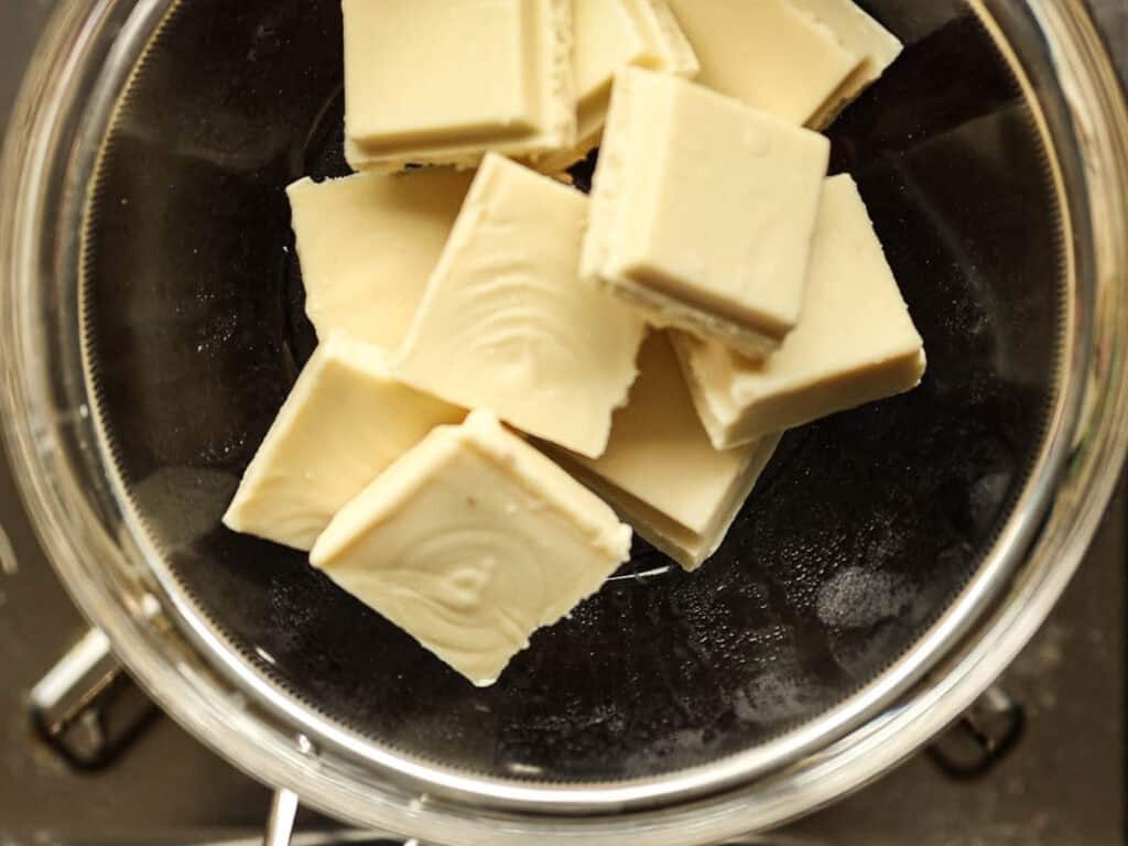 Viral Dubai Chocolate Bar with Strawberry Filling (Vegan). 12 Pieces of white chocolate stacked in a glass bowl, viewed from above.