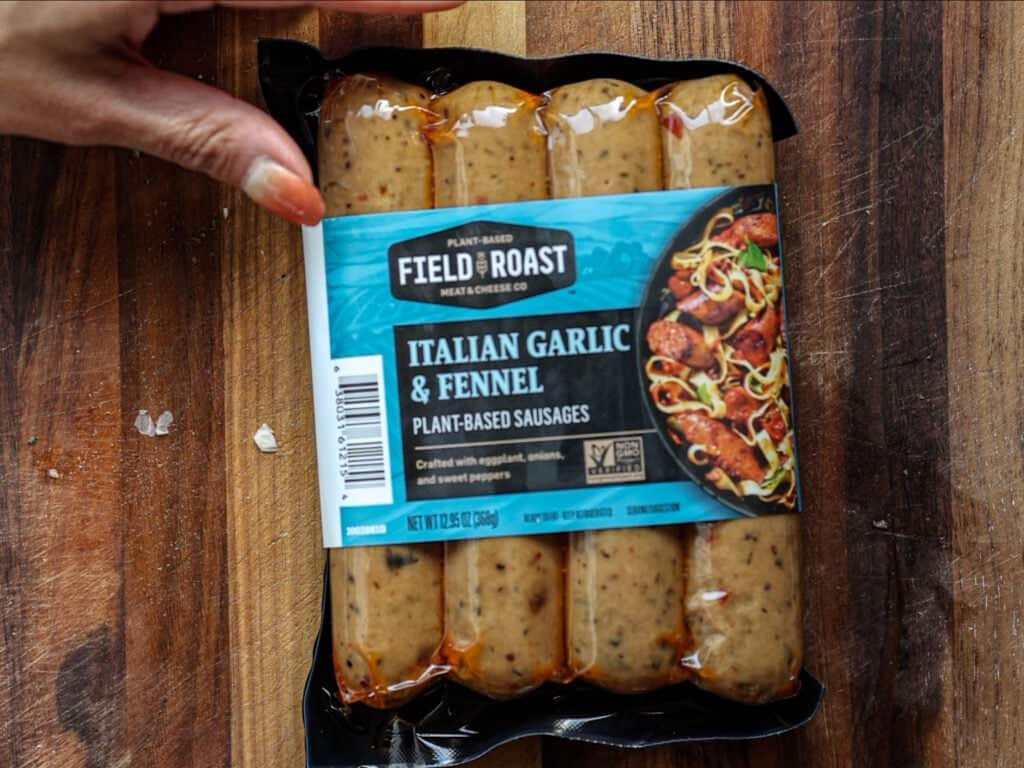Creamy Cozy Kale White Bean Soup (EASY & Vegan). 10 A hand holds a package of Field Roast Italian Garlic & Fennel plant-based sausages, showing four sausages inside and a blue label with product details and an image of cooked sausages.