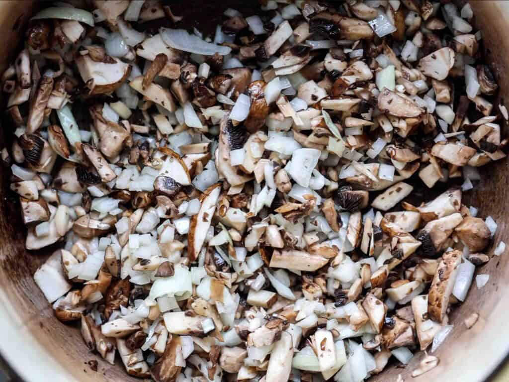 BEST Vegan Bolognese Recipe - Meaty and Delicious. 27 Chopped mushrooms and onions mixed together in a pot, ready to be cooked.