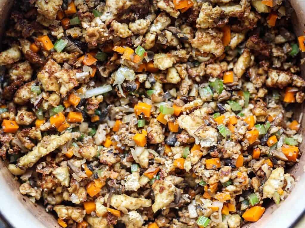 BEST Vegan Bolognese Recipe - Meaty and Delicious. 29 A close-up of a colorful stir-fry with diced carrots, onions, celery, and mushrooms and tofu, mixed together in a large pot.