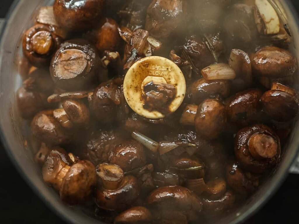 Cheesy Mushroom Rigatoni Pie - Easy Vegan Recipe. 26 A food processor bowl filled with sautéed mushrooms and chopped shallots, ready to be blended; the steam slightly fogs the view of the contents.