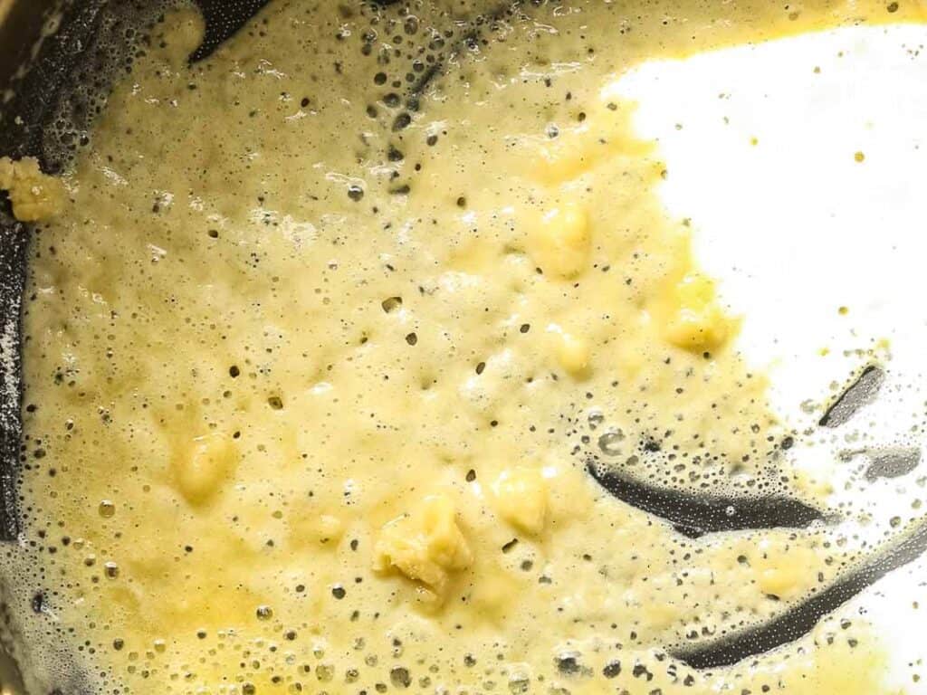 Cheesy Mushroom Rigatoni Pie - Easy Vegan Recipe. 30 A close-up of melted butter and flour being whisked together in a pan, forming a bubbly and slightly lumpy roux, commonly used as a base for sauces.