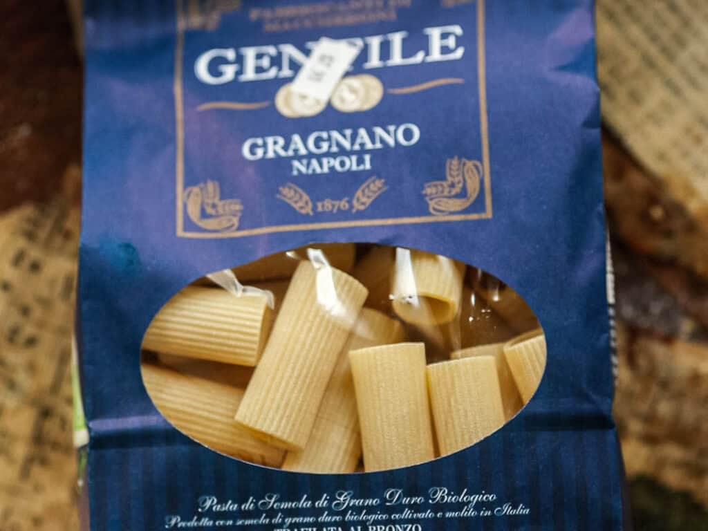 Cheesy Mushroom Rigatoni Pie - Easy Vegan Recipe. 4 A blue package of Gentile Gragnano Napoli pasta with a clear window showing tube-shaped pasta inside. The label indicates it is organic durum wheat pasta made in Italy.