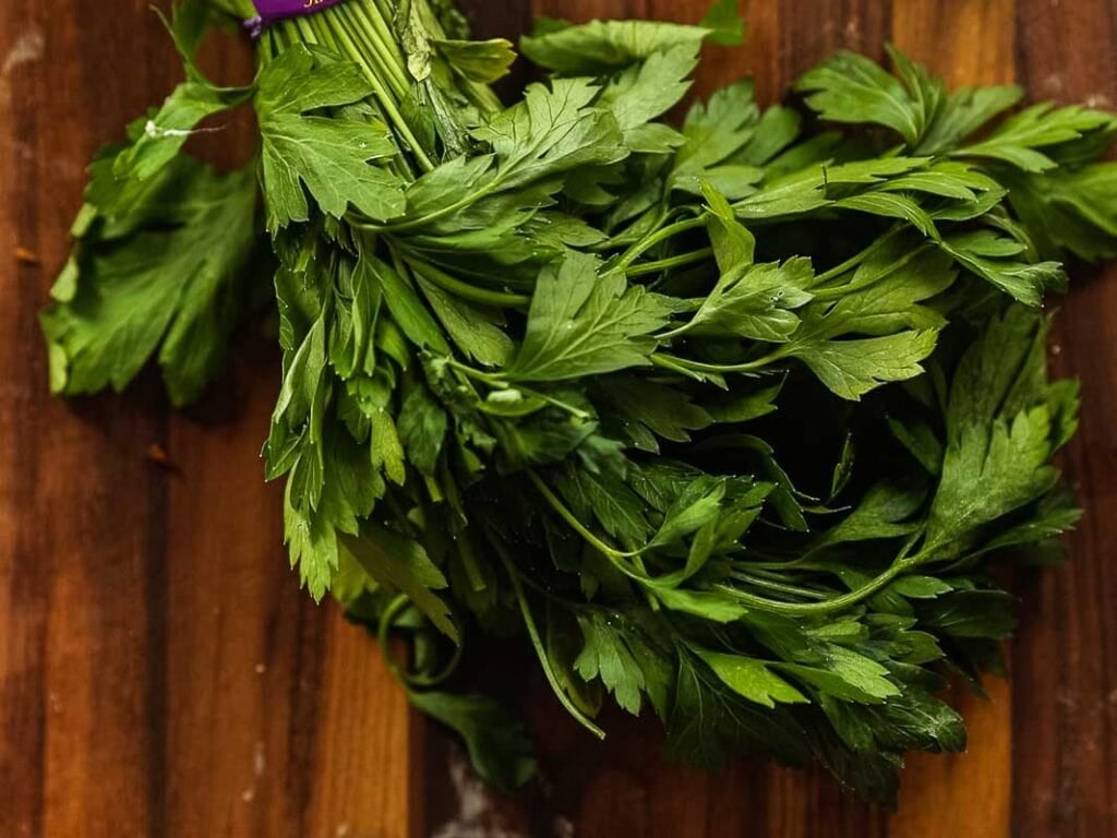 Cheesy Mushroom Rigatoni Pie - Easy Vegan Recipe. 9 A bunch of fresh parsley with green leaves sits on a wooden surface.