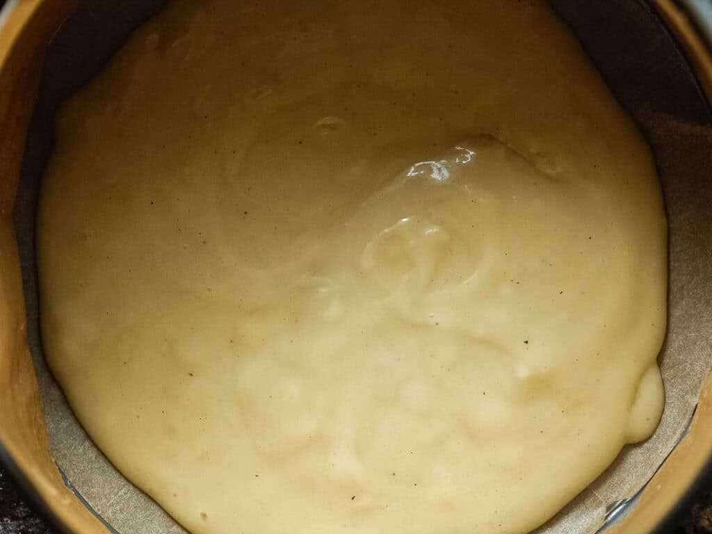 Cheesy Mushroom Rigatoni Pie - Easy Vegan Recipe. 40 A close-up of thick, creamy béchamel spread evenly in a round, parchment-lined baking tin, ready to be baked.