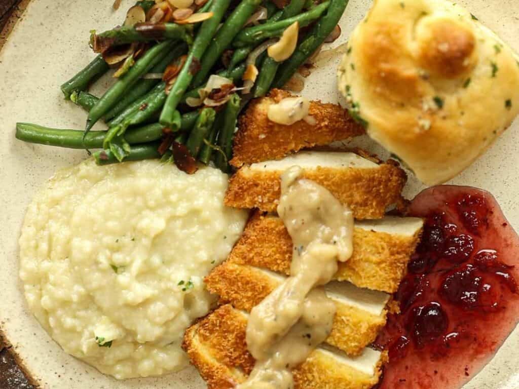 15-minute Quick and Easy Vegan Mushroom Gravy Recipe. 8 A plate with sliced breaded tof katsu topped with gravy, green beans with almond slivers, mashed potatoes, a dinner roll, and a serving of red berry sauce.