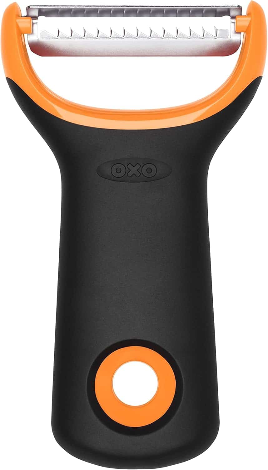 The Korean Vegan's 2025 VEGAN Holiday Gift GUIDE. 16 A black and orange OXO branded vegetable peeler with a wide stainless steel blade and ergonomic handle—an essential tool featured in the Korean Vegan 2025 holiday gift guide, designed for easy grip and efficient peeling.