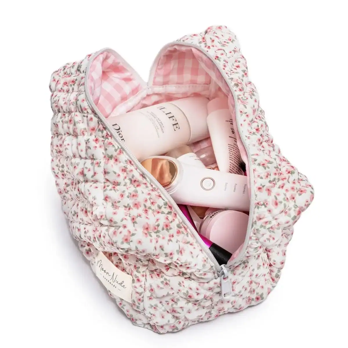 The Korean Vegan's 2025 VEGAN Holiday Gift GUIDE. 33 A quilted, floral-patterned cosmetic bag with a pink checkered lining, unzipped to reveal various Korean vegan skincare and beauty products inside.