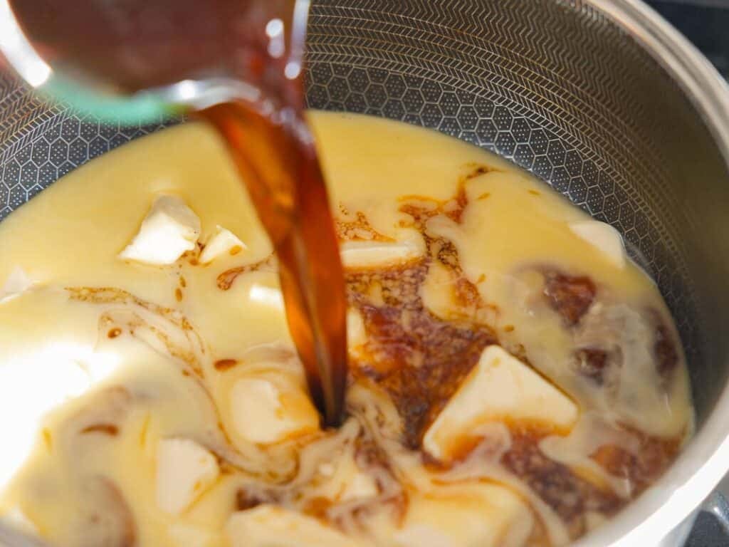 The BEST Vegan Chocolate Cake Recipe On The Internet. 8 A close-up of coffee being poured into a pot containing sweetened condensed milk and pieces of butter, ready to be mixed and cooked.