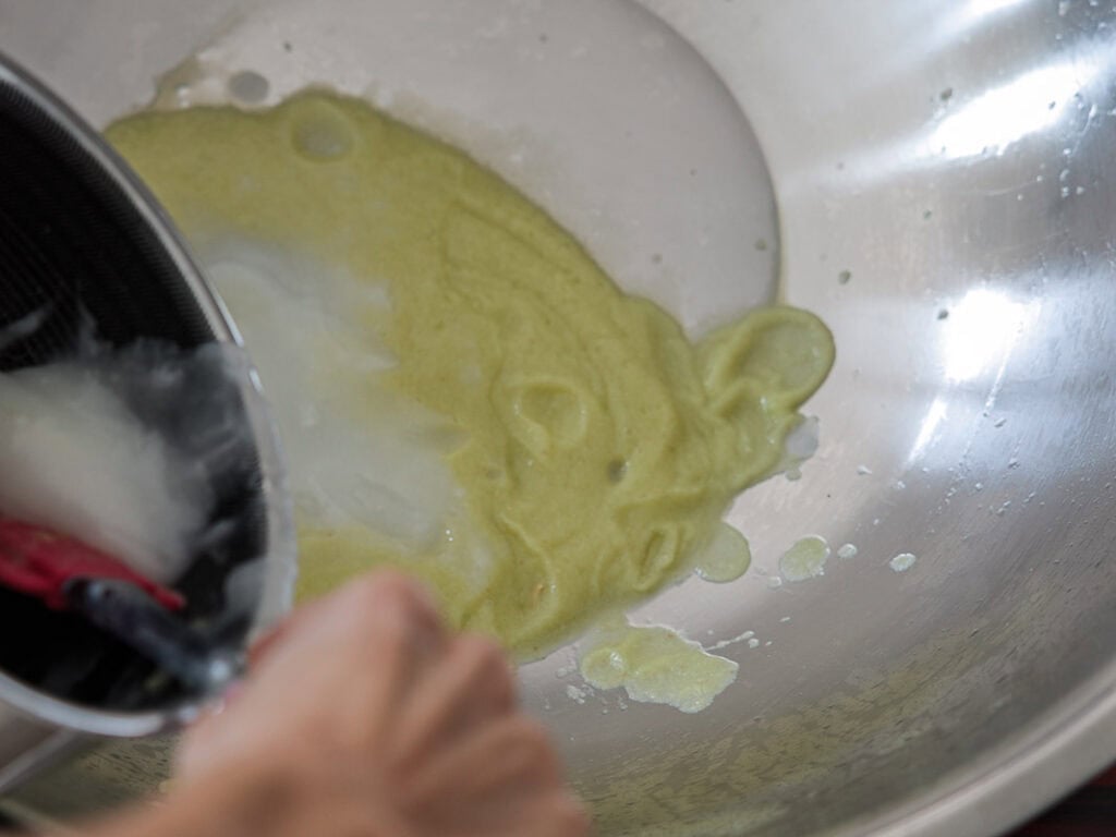 Vegan Ponytail Kimchi aka Chonggak-Kimchi Recipe. 36 A person pours a white liquid from a black container into a large metal bowl containing a pale green, thick vegan kimchi mixture.