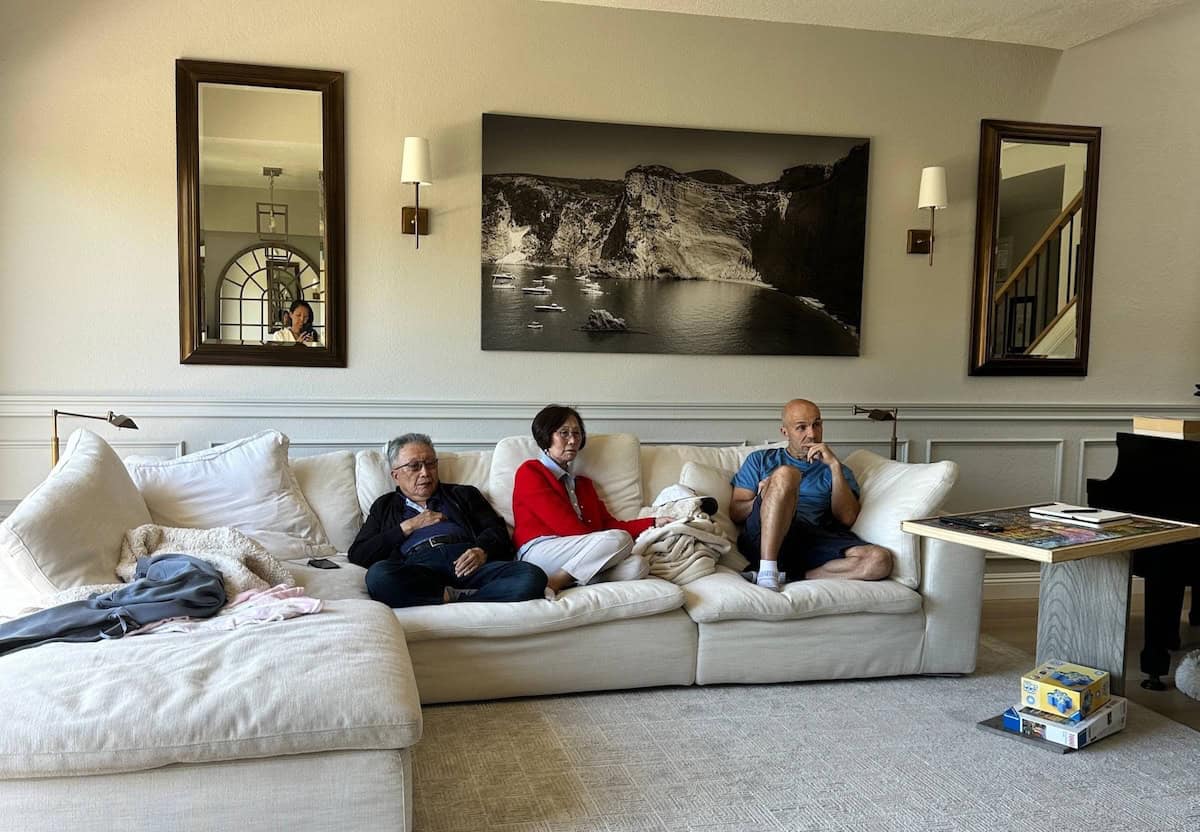 The FCC, First Amendment, and Censorship. 2 Three adults relax on a large white sectional sofa, possibly discussing First Amendment issues as they watch something offscreen. A dog lies between them, and a table with board games sits nearby beneath two mirrors and a black-and-white landscape photo.